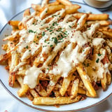 A plate of french fries covered in cheese and seasoning.