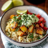 A bowl of rice with vegetables and a sauce.