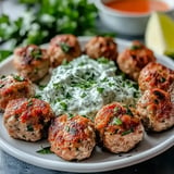 A plate of meatballs with a white sauce and a bowl of soup.